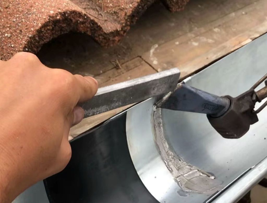 Soudure d'un raccord de zinc sur une gouttière par un zingueur